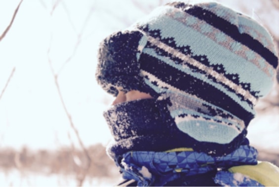 kleines Kind im Winter mit blauer Mütze und Schal