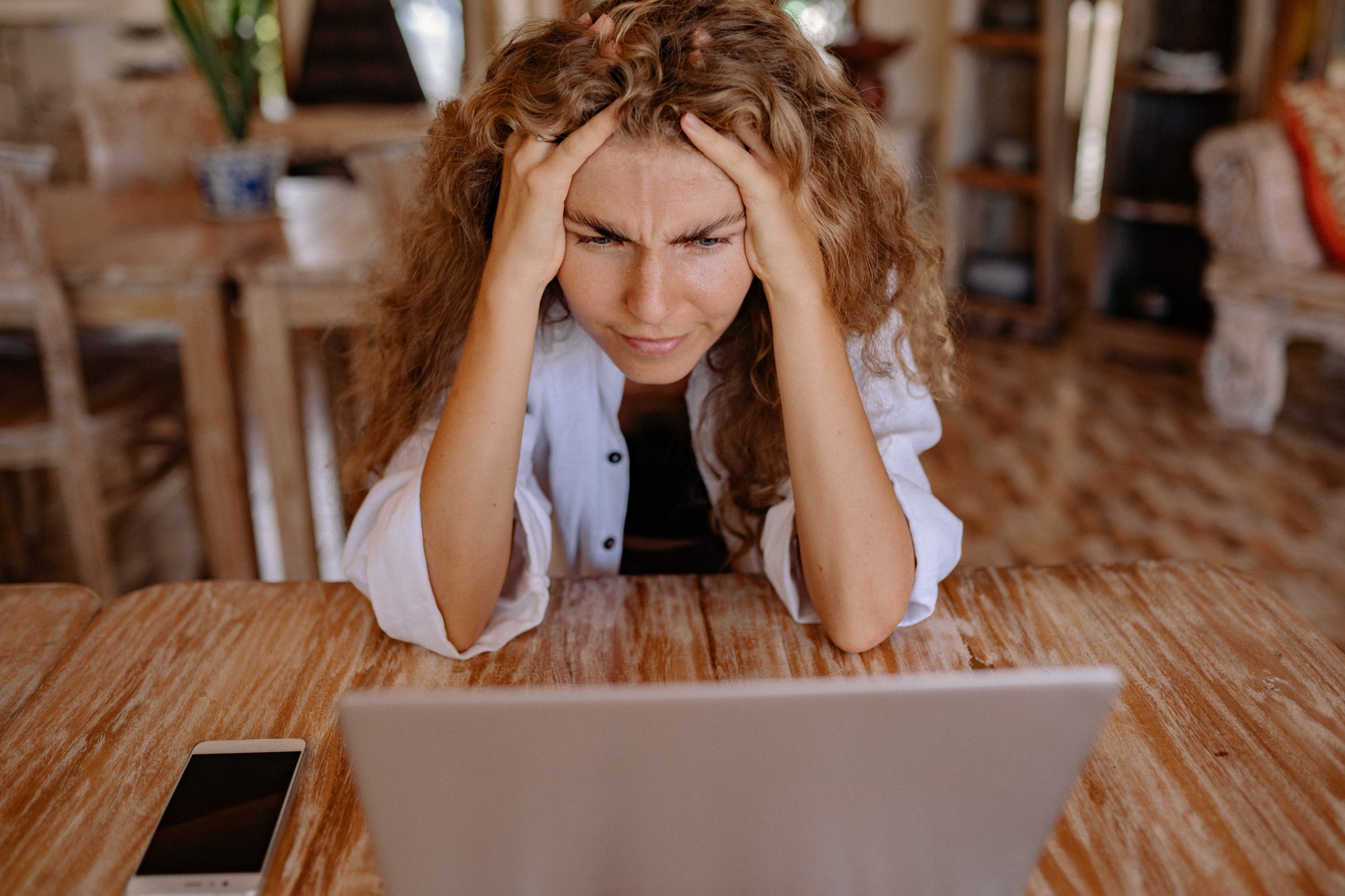 Frau sitzt vor Laptop und hat Kopfschmerzen. Machen hochfrequente Funkwellen krank?