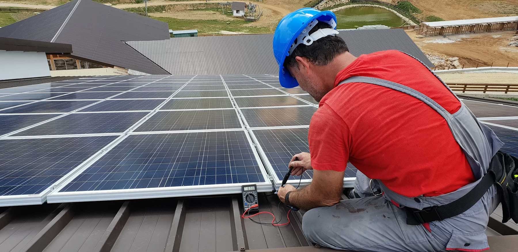Mann installaiert eine Photovoltaikanlage auf dem Dach.